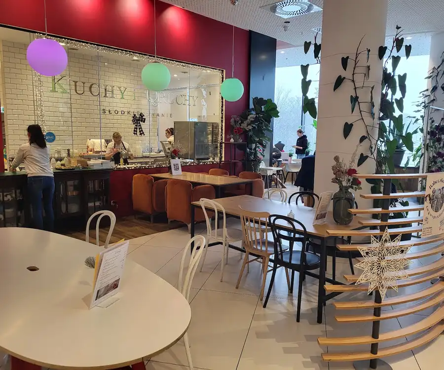 Bistro w galerii: czerwona ściana, przeszklona kuchnia i kolorowe lampy-kule